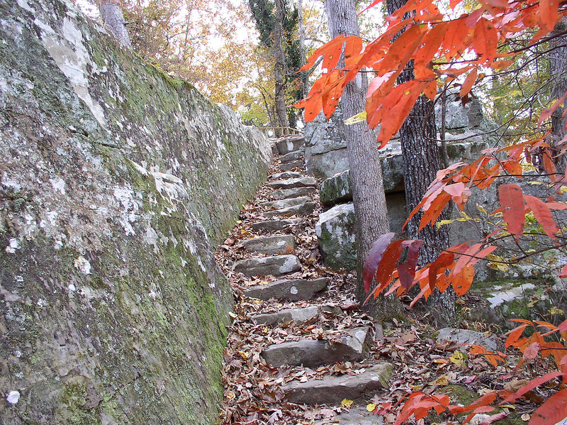 Outcroppings trail featuring stone steps leading up a hill shadowed by orange autumn leaves.
