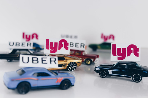 Toy cars with paper logos of Uber and Lyft put on top