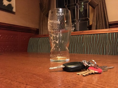 Empty pint of beer on a restaurant table next to a set of car keys