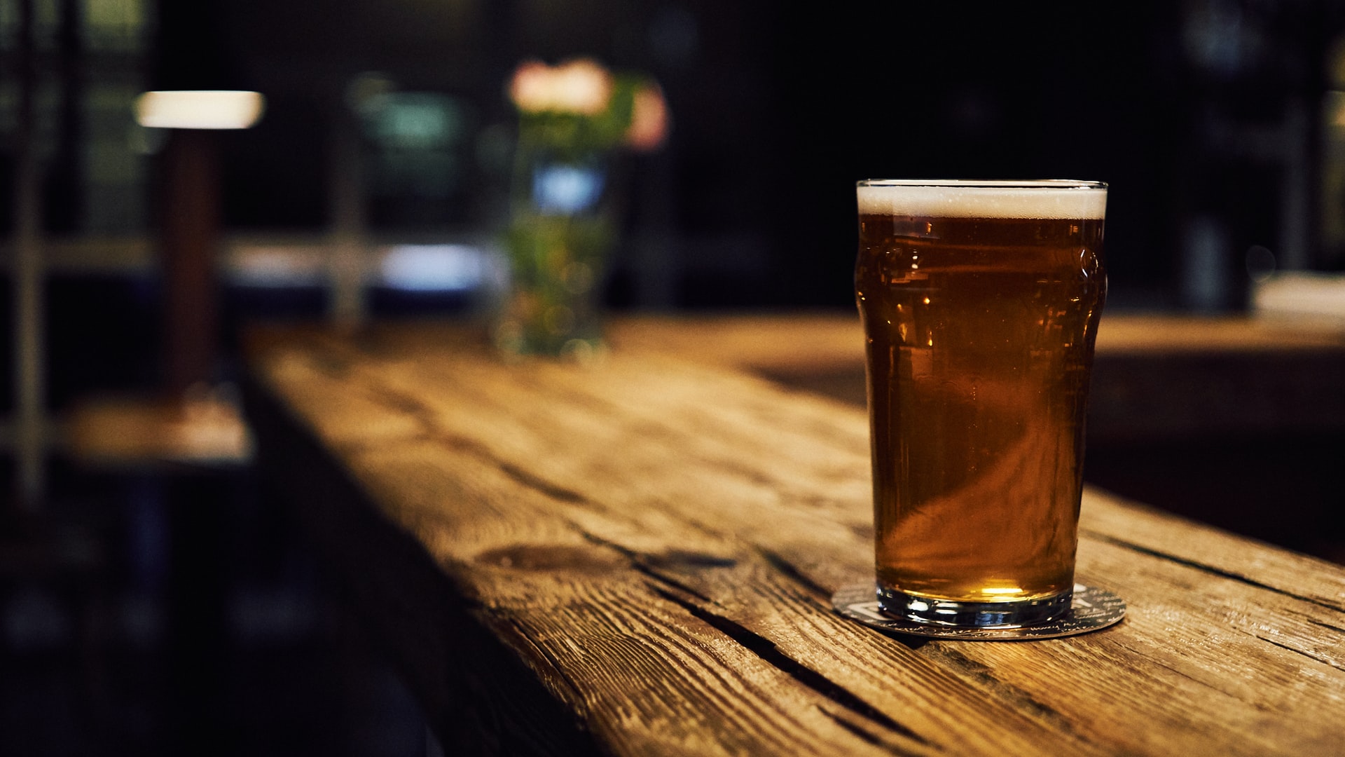 Full beer pint on wooden bar in dark tap room