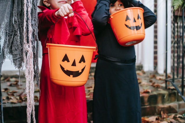 2 kids sin costumes with Halloween buckets for candy