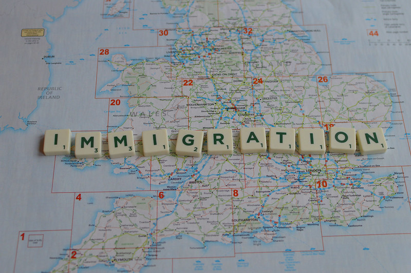 Scrabble letters spelling out Immigration over a map of the UK.