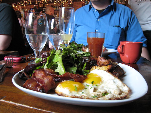 Plate with over-easy eggs, bacon, potatoes, and greens at brunch restaurant