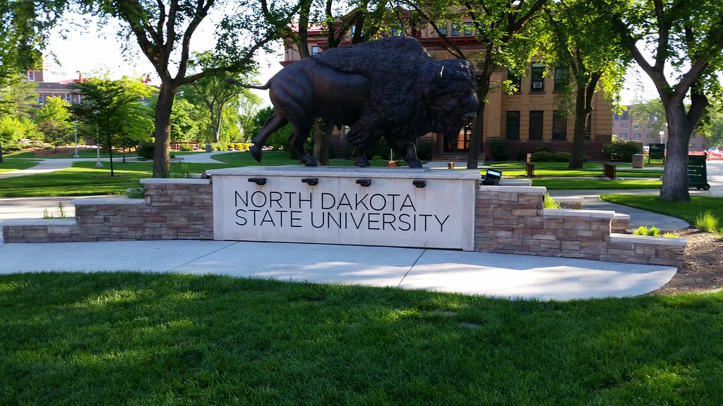 Stone sign with "North Dakota State University" carved on the front with a bull statue above it