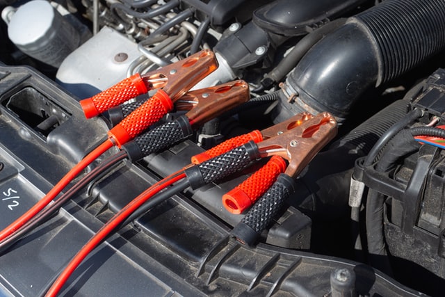 A set of red and black jumper cables attached to a car battery