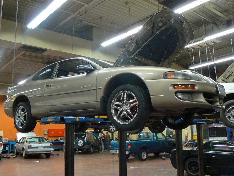 Car lifted in body shop with hood up for certified auto body work