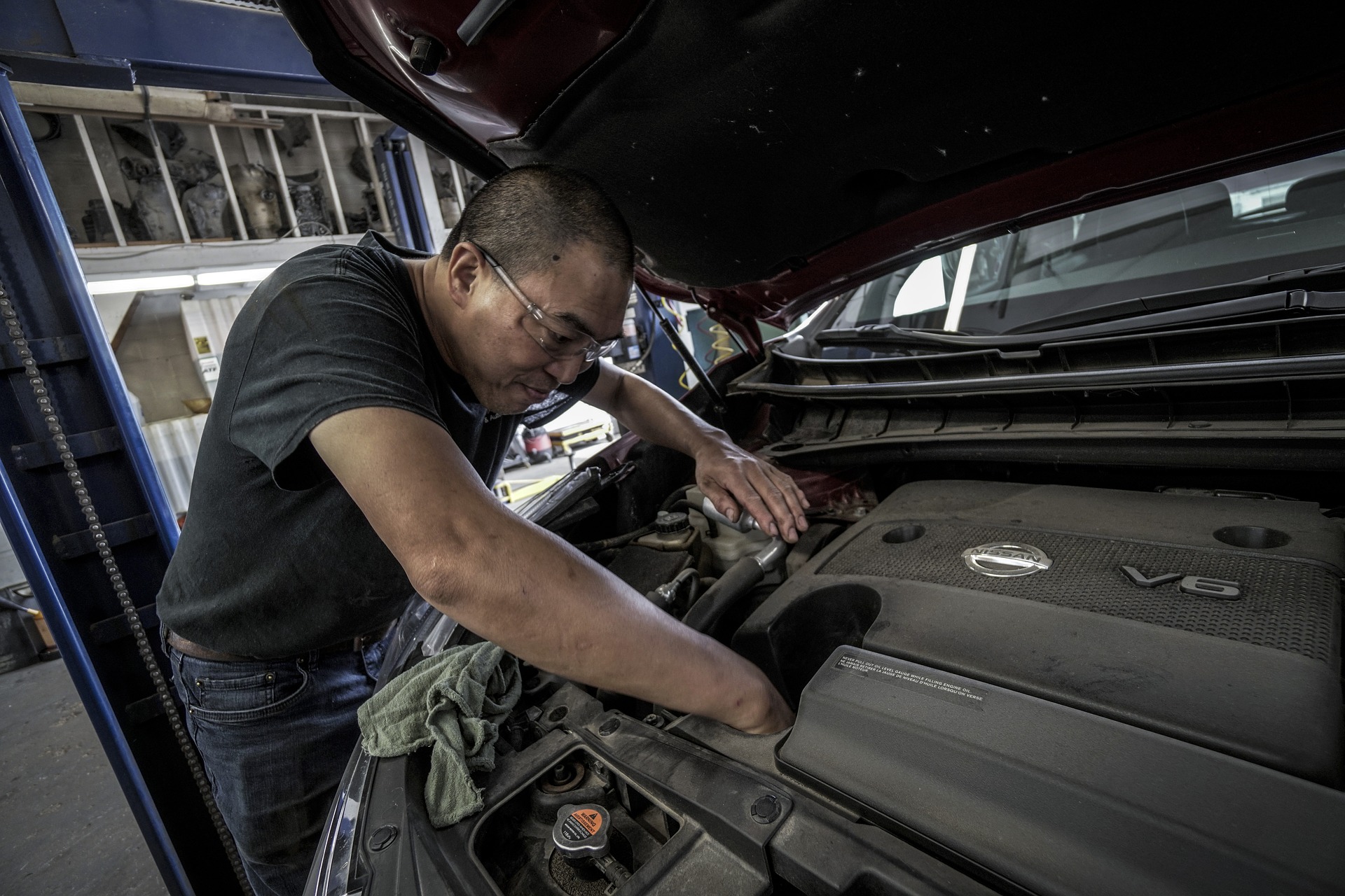 Mechanic with goggles inspecting used car's engine